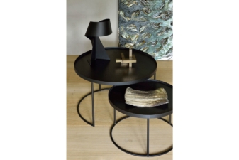 Modern black nesting coffee tables with slim metal frames, styled with sculptural decor and placed on light wood flooring next to abstract wall art.