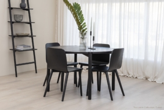 Minimalist dining room with a round black wooden dining table nz and matching black chairs, styled with a modern vase centerpiece and leaning ladder shelf, set against sheer white curtains. modern furniture from cuchi nz